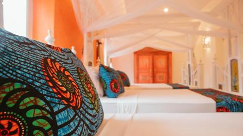 a bedroom with two beds with colorful pillows at Villa Hibiscus Zanzibar in Jambiani