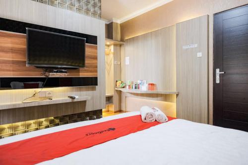 um quarto com uma cama e uma televisão de ecrã plano em RedDoorz Plus @ Simpang USU Medan em Medan