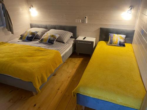 two beds in a small room with yellow blankets at Domki Mechelinki in Mechelinki