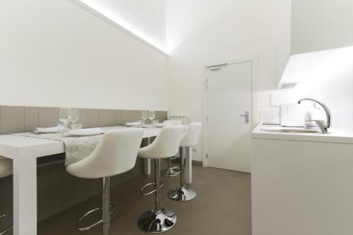 a white kitchen with white counters and white stools at Palazzo dei Ciompi Suites in Florence