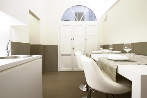 a white kitchen with a table and white chairs at Palazzo dei Ciompi Suites in Florence
