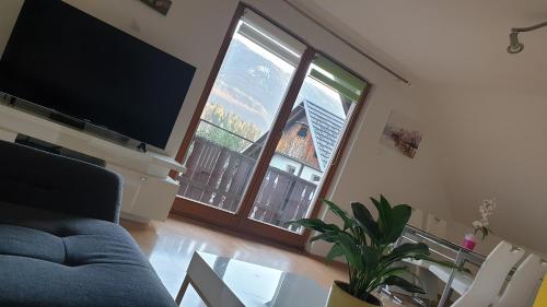 a living room with a couch and a tv and a table at Apartments Lake Bohinj Medja in Bohinj