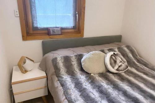 ein Schlafzimmer mit einem Bett mit einer Decke und einem Fenster in der Unterkunft Appartement de charme dans résidence avec piscine La Joue du Loup in Le Dévoluy