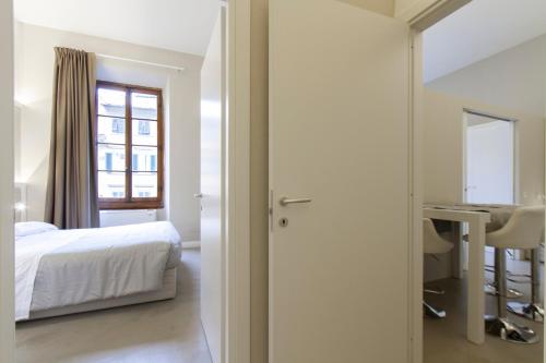 a bedroom with a bed and a desk and a window at Palazzo dei Ciompi Suites in Florence