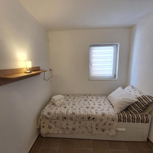 a small bedroom with a bed and a window at Kuća za odmor Zip in Murter