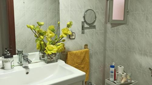 baño con lavabo y jarrón de flores amarillas en Alojamiento Rumfox, en Jaén