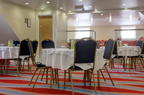 a group of tables and chairs in a room at Best Western Greater London in Ilford
