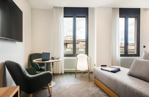 ジローナにあるペニンスラールのベッド、テーブル、窓が備わるホテルルームです。