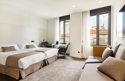Habitación de hotel con 2 camas, mesa y sillas en Peninsular, en Girona