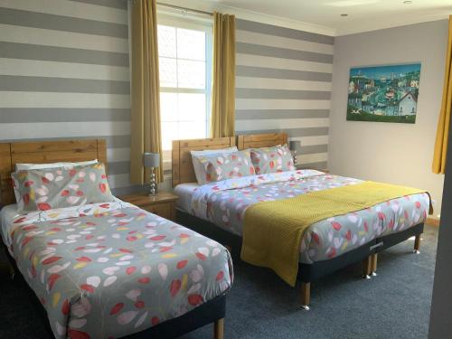 two beds in a room with striped walls at Southbank Guesthouse in Elgin