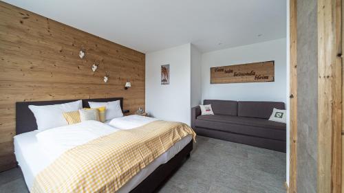 a bedroom with a large bed and a couch at VIERKLEE - Das kinderfreundliche Ferienhaus am Achensee in Maurach