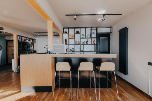 a kitchen with a bar with white stools at Quadrum Hotel in Gudauri