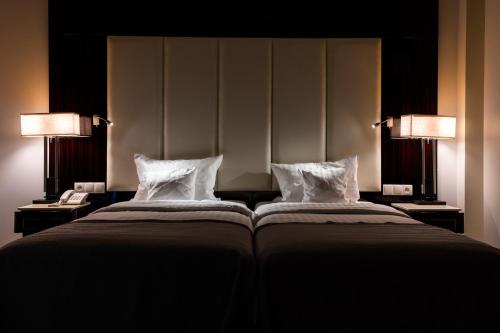 a bedroom with two beds with pillows and two lamps at Natura Mazur Resort & Conference in Warchały