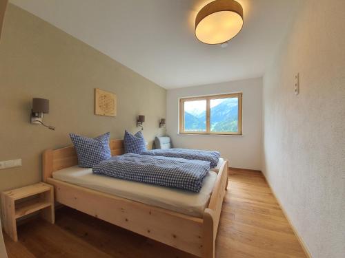 a bedroom with a bed with blue pillows and a window at Appartment Sonnenwiese in Finkenberg