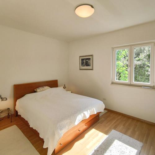 a bedroom with a large bed and two windows at Seaside House PuntaSkala in Petrcane