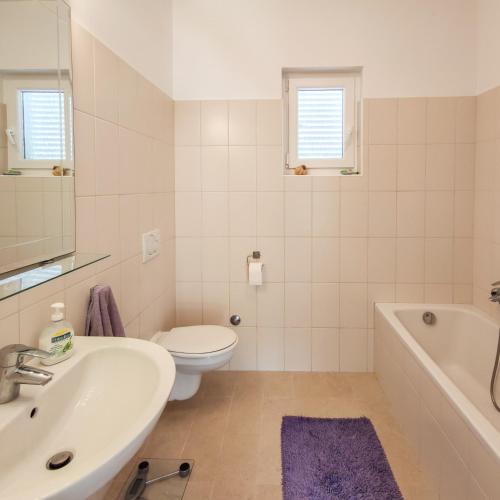 a bathroom with a sink and a toilet and a tub at Seaside House PuntaSkala in Petrcane