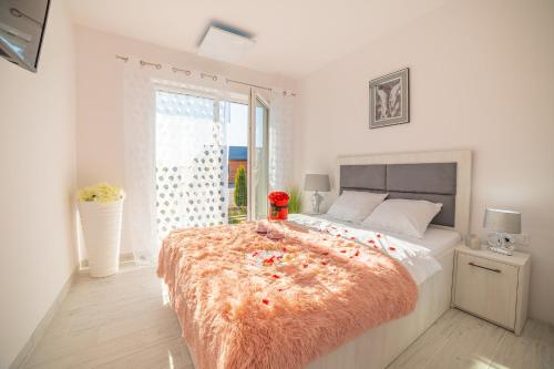 a bedroom with a large bed with an orange blanket at Apartamenty Scarlet in Darłowo
