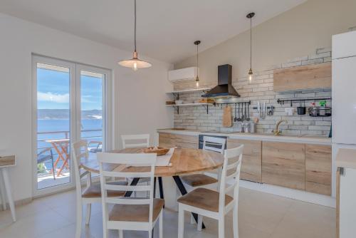 a kitchen with a wooden table and white chairs at Apartments Jadranka in Mimice