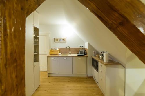 an attic kitchen with white cabinets and a sink at Aparthotel & Wellness Knížecí cesta in Horní Planá