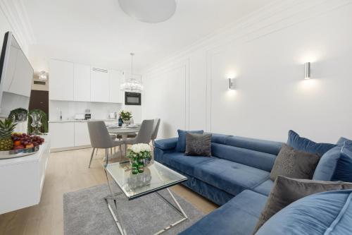 - un salon avec un canapé bleu et une table dans l'établissement Apartament Baltini Premium Polanki Park, à Kołobrzeg