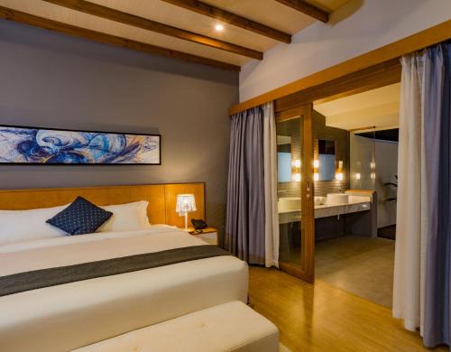 a bedroom with a bed and a bathroom at Fiyavalhu Resort Maldives in Mandhoo