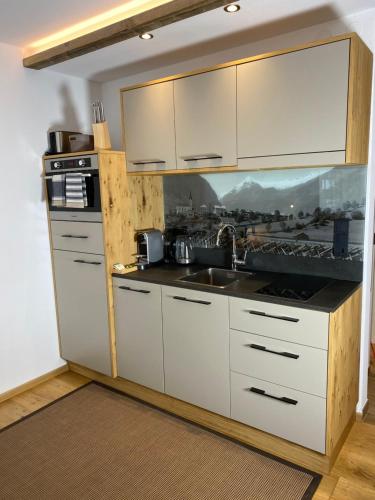 a kitchen with white cabinets and a sink at Apartment Luna incl Summercard Zell am See Kaprun in Kaprun