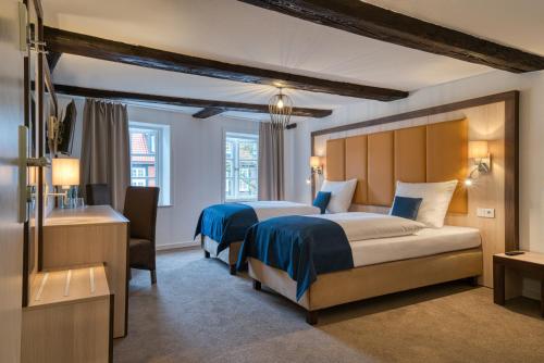 a hotel room with two beds and a desk at Hotel Am Fischmarkt in Stade