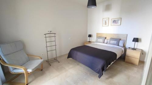 een slaapkamer met een bed, een stoel en een ladder bij Valle Romano Golf Resort Estepona in Estepona