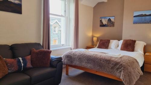 1 dormitorio con cama, sofá y ventana en Herdwick Guest House, en Keswick
