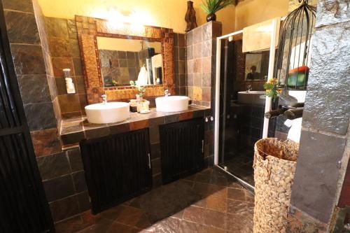 Baño con 2 lavabos y espejo en African Rock Lodge, en Hoedspruit