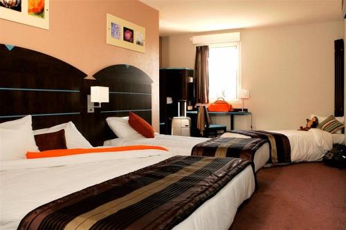 een hotelkamer met 2 bedden en een raam bij Hôtel Akena City Caudry in Caudry