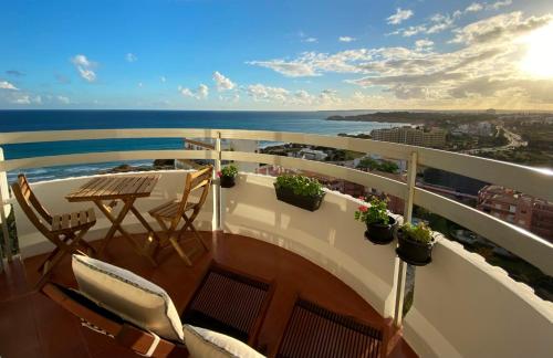 a balcony with a table and chairs and the ocean at 3 Castelos Sunset - Praia da Rocha in Portimão