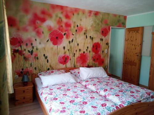 a bedroom with a bed with red flowers on the wall at Ferienwohnungen Schenk Schmitz in Bad Bertrich