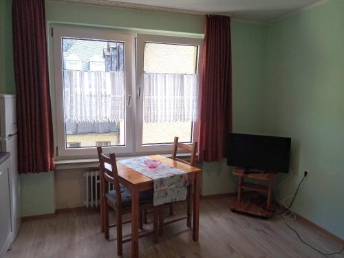 a dining room with a table and a television at Ferienwohnungen Schenk Schmitz in Bad Bertrich