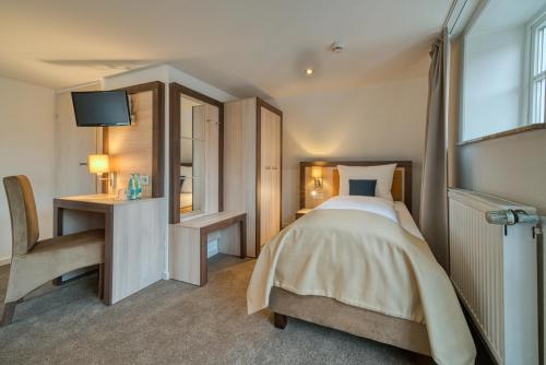 a bedroom with a bed and a desk and a television at Hotel Am Fischmarkt in Stade