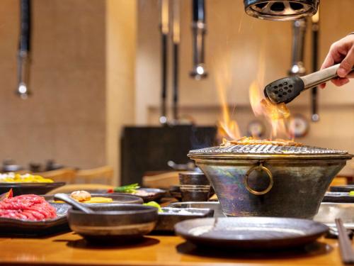 a person cooking food in a pot on a table at Pullman Changbaishan Resort in Fusong