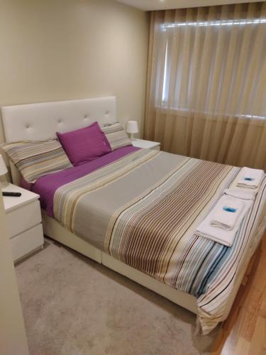 ein Schlafzimmer mit einem großen Bett mit lila Kissen in der Unterkunft Furadouro Beach Spot in Ovar