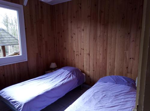 two beds in a room with wooden walls and a window at REPERE D'ALL in Sainte-Croix-sur-Orne