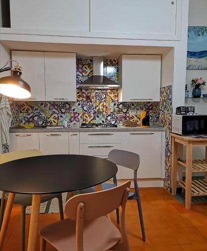 a kitchen with white cabinets and a table and chairs at Annina Home in Paestum