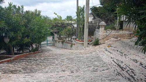 a cobblestone street with a fence and trees at casa dei limoni in Peschici