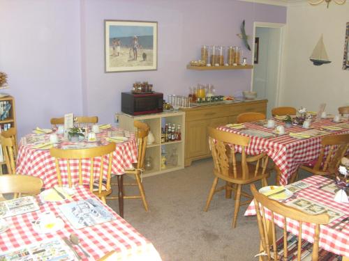 a dining room with two tables with red and white checkered table cloths at Ashdene Guest House in Southampton