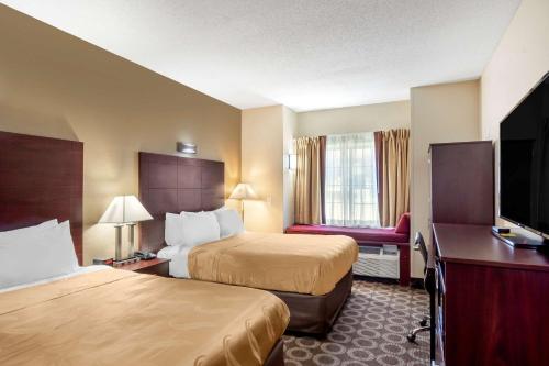a hotel room with two beds and a flat screen tv at Quality Inn Overland Park Kansas City in Overland Park