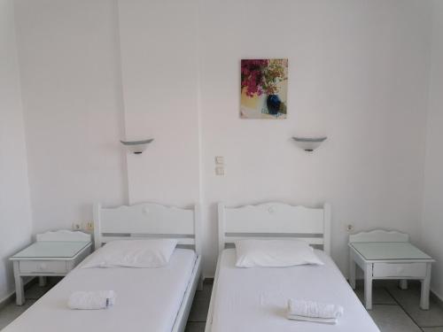 two beds in a room with white walls at Flora Apartments & Studios in Agia Anna Naxos