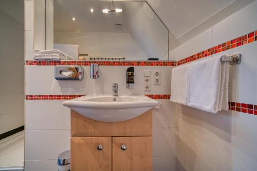 a bathroom with a sink and red and white tiles at Hotel Am Fischmarkt in Stade