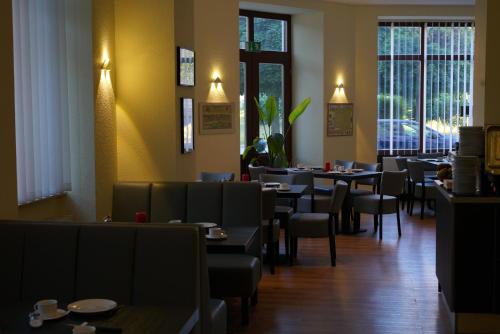 a dining room with tables and chairs and windows at Gästehaus Lisakowski Pension am Brautwiesenpark in Görlitz