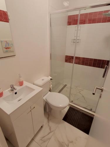a white bathroom with a toilet and a shower at Village Cascais Guest House in Cascais