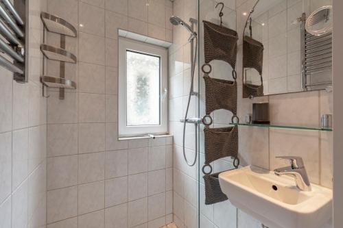 uma casa de banho branca com um lavatório e um chuveiro em Klaproos - Groote Keeten em Callantsoog