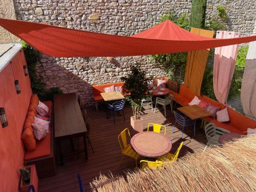 a patio with tables and chairs and a red tent at Coco Marco Hôtel in Nyons