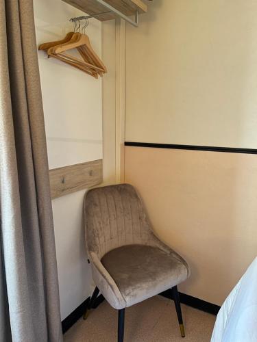 a chair sitting in a bedroom next to a window at Coco Marco Hôtel in Nyons