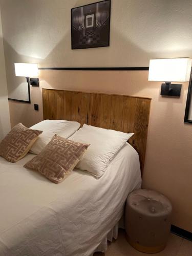 a bedroom with a bed with two pillows and two lamps at Coco Marco Hôtel in Nyons